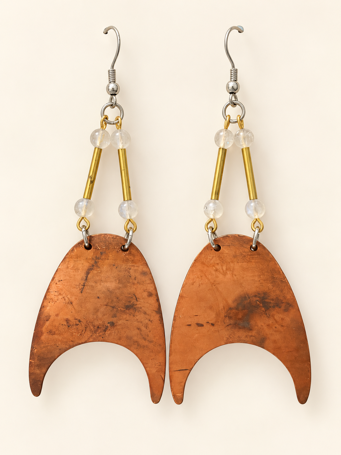 Large patinated copper crescent earrings suspended from brass tubes and pale moonstone beads.